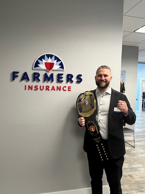 James Foster Standing with a Farmers insurance award belt in his office in colorado springs